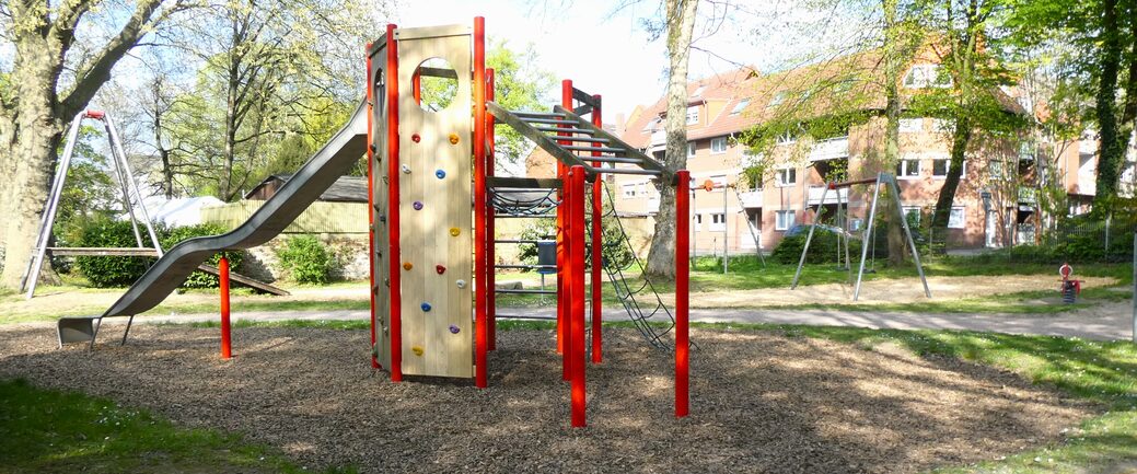 Der Spielplatz nach der Umgestaltung. Zu sehen ist ein Klettergerüst, eine Seilbahn und eine Rutsche-