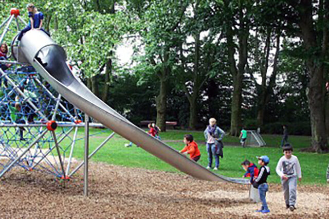 Der neu gestaltete Spielplatz. Man sieht spielende Kinder rund um und auf einem Klettergerüst mit Rutsche.