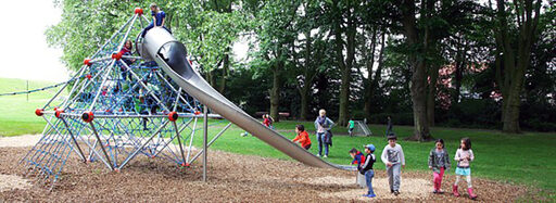 Der neu gestaltete Spielplatz. Man sieht spielende Kinder rund um und auf einem Klettergerüst mit Rutsche.