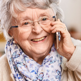 Eine lächende, ältere Dame am Telefon