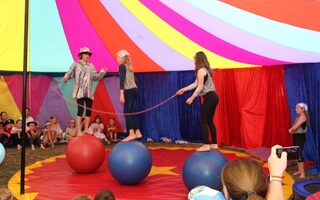 Drei auf Bällen balancierende Jugendliche in einem Zirkuszelt
