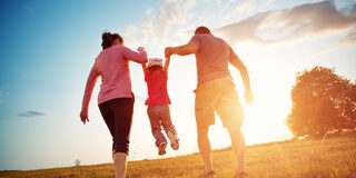 girl with mother and father holding hands on the nature