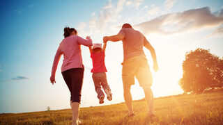 girl with mother and father holding hands on the nature
