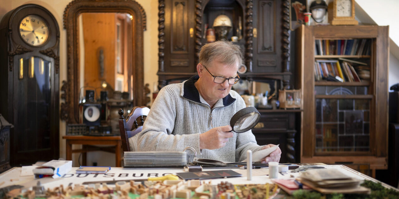 Mit der großen Lupe untersucht Reinhold Stausberg seine Postkarten