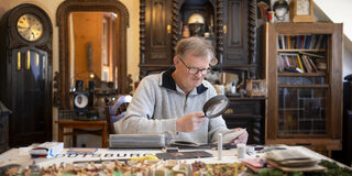 Mit der großen Lupe untersucht Reinhold Stausberg seine Postkarten