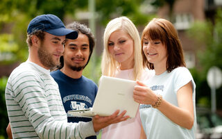 Vier Studenten die auf ein Macbook schauen