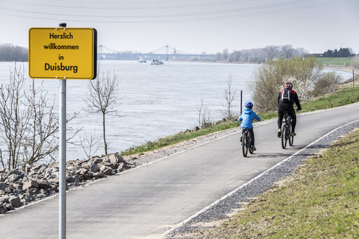 Personen die Fahrrad fahren und im Hintergrund ist der Rhein