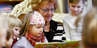 Frau liest Kindern aus einem Buch vor.