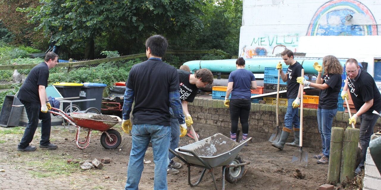 Männer und Frauen reissen ein Beet ab.