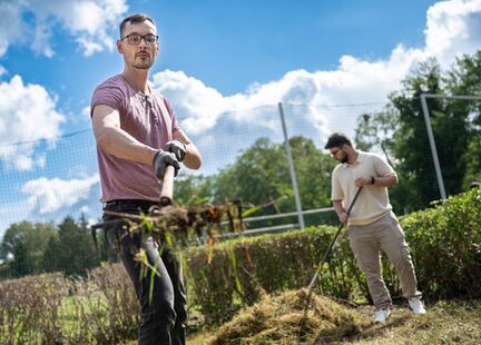 Zwei Auszubildende befreien die Platzanlage von Unkraut