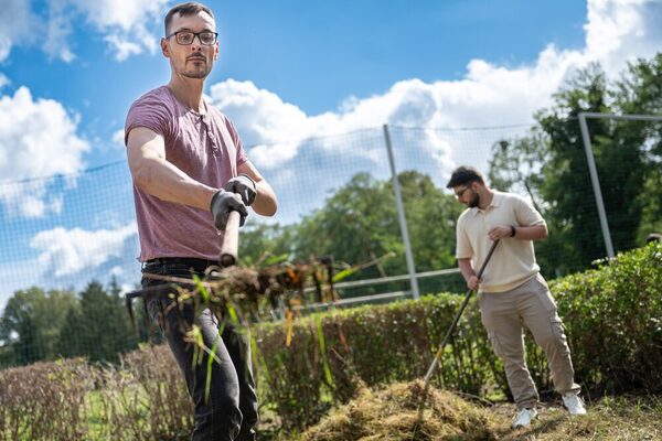 Zwei Auszubildende befreien die Platzanlage von Unkraut