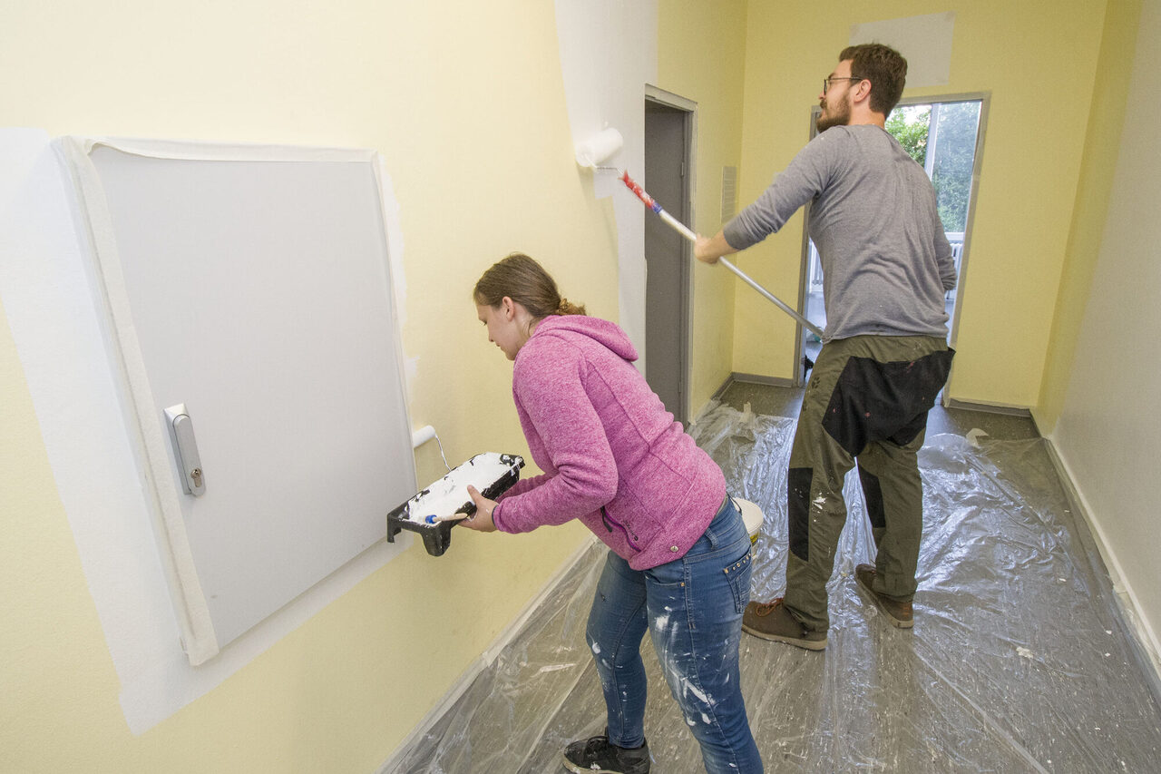 zwei Menschen streichen eine Wand