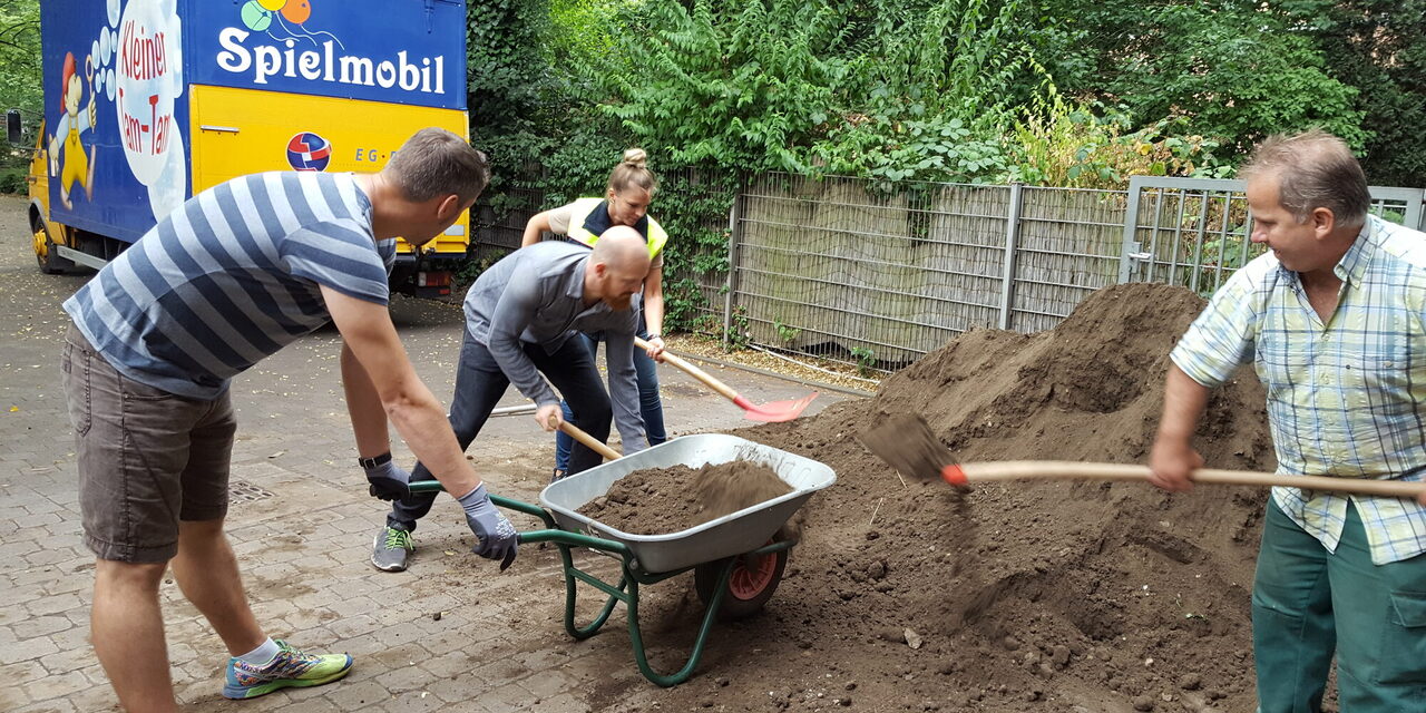 Menschen schaufeln Erde in eine Schubkarre