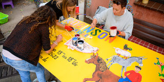 Drei Frauen malen ein neues Eingangsschild.