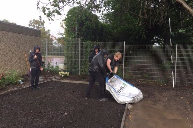 Mitarbeiter arbeiten bei Regen im Schulgarten