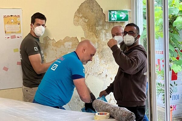 Vier Mitarbeiter bei der Sanierung einer Wand.