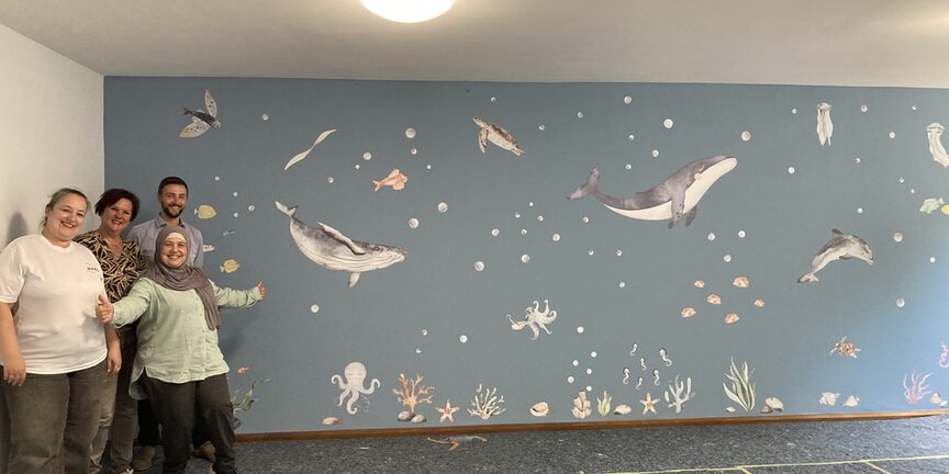 Mitarbeitende präsentieren die fertig gestaltete Wand.