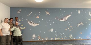 Mitarbeitende präsentieren die fertig gestaltete Wand.