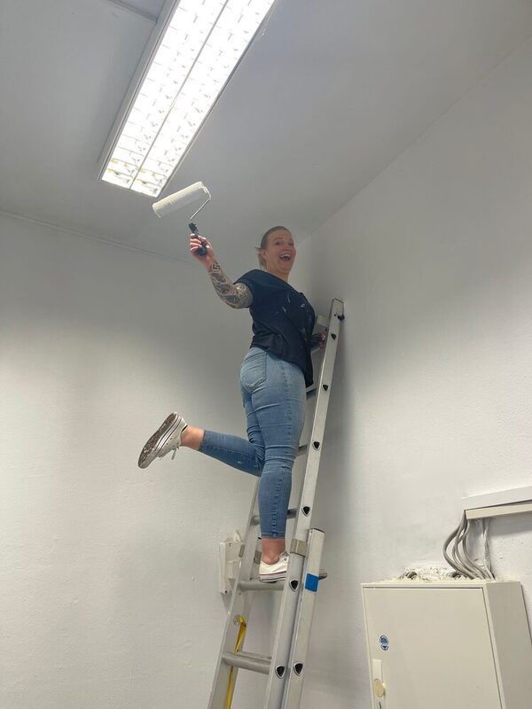 Eine Mitarbeiterin der Targo Bank steht auf der Leiter und streicht die Wand