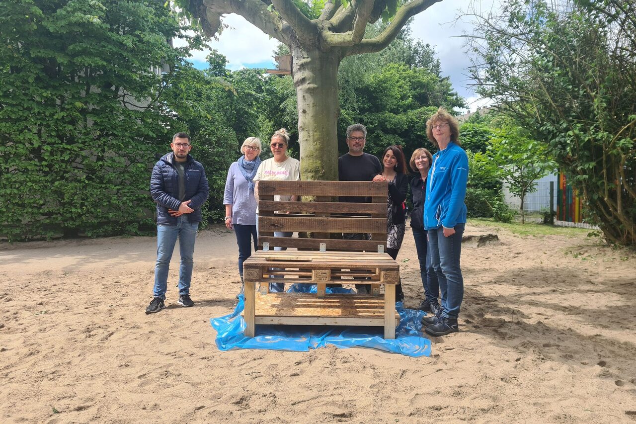 Gruppenfoto mit den Mitarbeitenden von Total Energies und der Leiterin der Kindertageseinrichtung vor der fast fertigen Matschküche