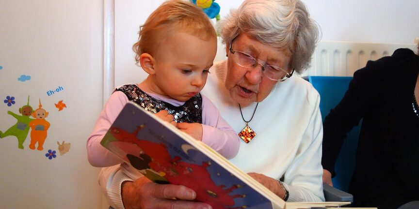 Eine ältere Dame liest einem Kleinkind vor