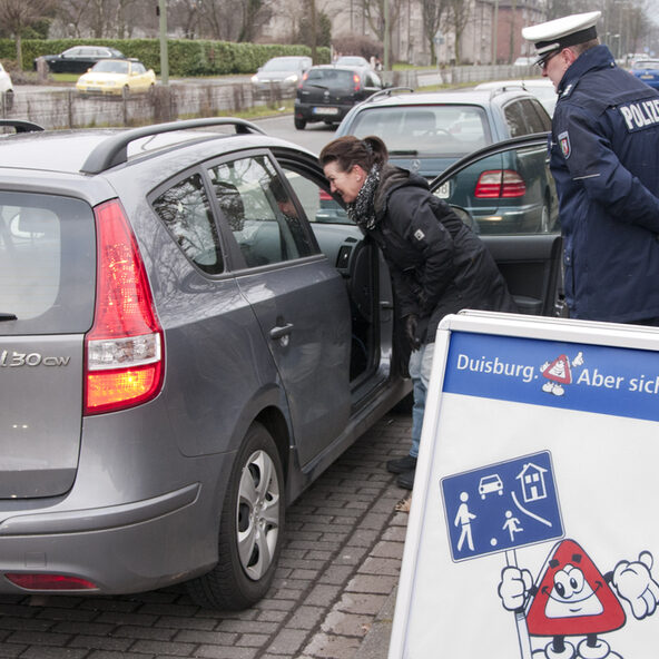 Eine Mitarbeiterin der Stadt Duisburg und ein Polizeibeamter geben vor der Schule Tipps zum richtigen Verhalten.