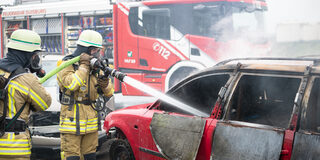 Feuerwehrleute löschen ein Auto