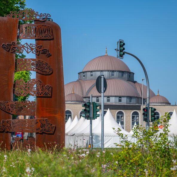 Die Dialogskulptur von Yildirim Denizli, im Hintergrund ist die Moschee zu sehen