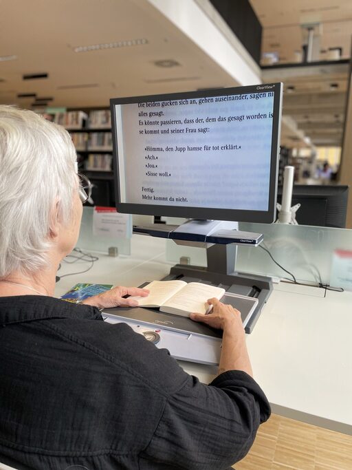Eine Frau sitzt vor einem Bildschirmlesegerät