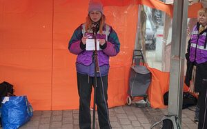 Eine Frau steht unter einen orangefarbenen Pavillon und spricht in ein Mikrofon