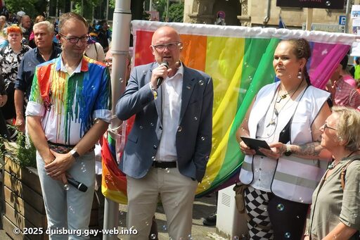 Vier Personen u.a. Oberbürgermeister Sören Link vor der Regenbogenflagge