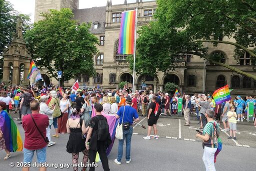 Menschen vor dem Rathaus beim Hissen der Regenbogenflagge