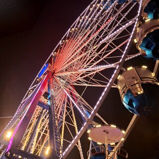 Riesenrad beleuchtet im Dunklen von oben nach unten
