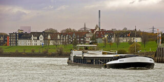 Binnenschiff "Mergus" auf dem Rhein vor der Einfahrt in den Ruhrorter Hafen. Im Hintergrund der Ortsteil Laar