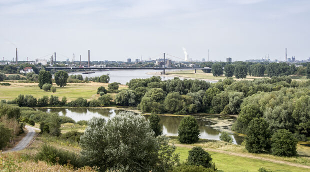 Blick von der Krupphalde II bei Rheihausen in nördlicher Richtung in das Rheinvorland mit edr Werthauser Wardt, der Autobahnbrücke im Zuge der A40 und der Stadtteil Homberg im Hintergrund. Am Horizont ist der Kühlturm des Kraftwerks Walsum und die Industrieanlagen von ThyssenKrupp Steel zu erkennen.