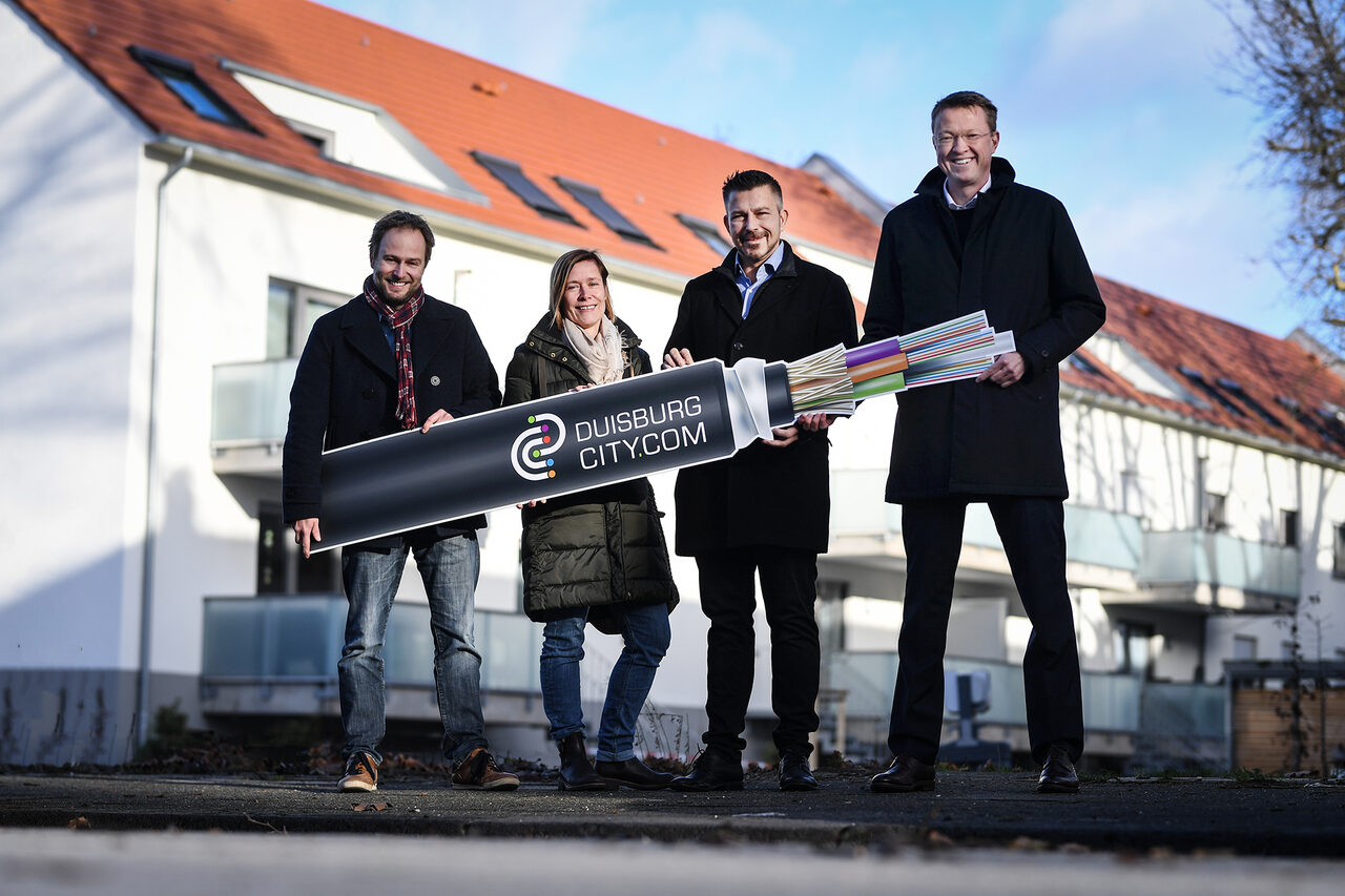 Glasfaser bis in die Mietwohnung: Stadtdirektor Martin Murrack, GEBAG-Prokuristin Sabine Störch, DCC-Geschäftsführer Stephan Soldat und DVV-Geschäftsführer Marcus Vunic (v. l.) vor den ersten komplett mit Breitbandtechnologie versorgten GEBAG-Immobilien in der Verdistraße.