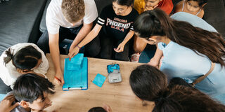 Kinder und Jugendliche sitzen um einen Tisch