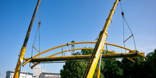 Zwei Kräne heben die neue Brücke ein