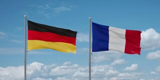 Deutsche Flagge links gehisst vor blauem Himmel, rechts daneben eine französische Flagge