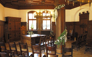 Trauzimmer mit dunklen Stühlen und Tischen und floralem Wandschmuck