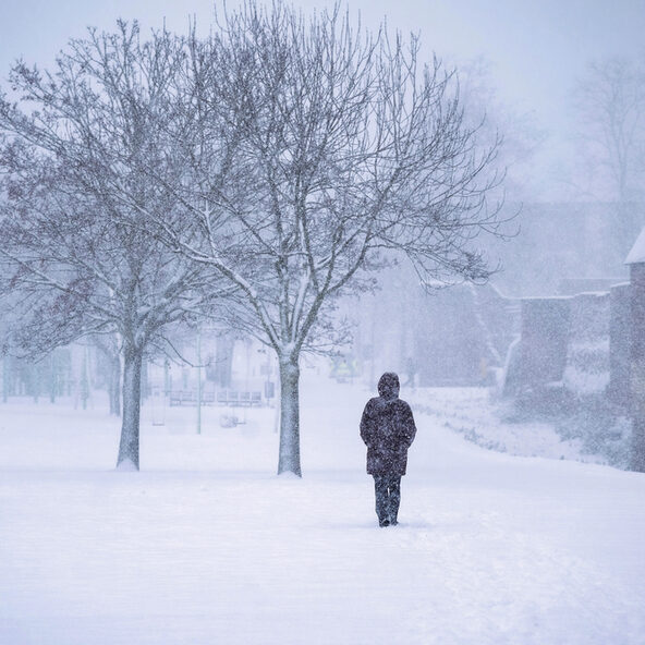 Einsamer Mensch spaziert durchs Schneetreiben