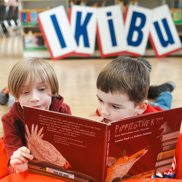 Kinder lesen zusammen in einem Buch während IKiBu