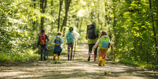Eine Frau und drei Kinder im Wald.