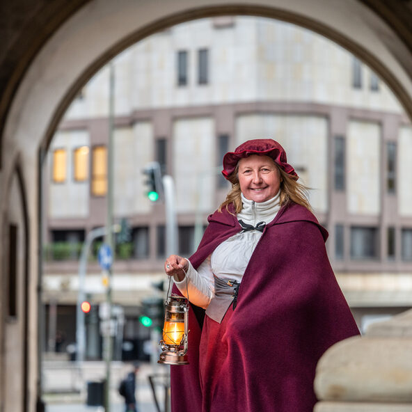 Eine Gästeführerin im Kostüm der vermeintlichen Hexe Agnes Muisfeltz mit einer Laterne in der Hand.