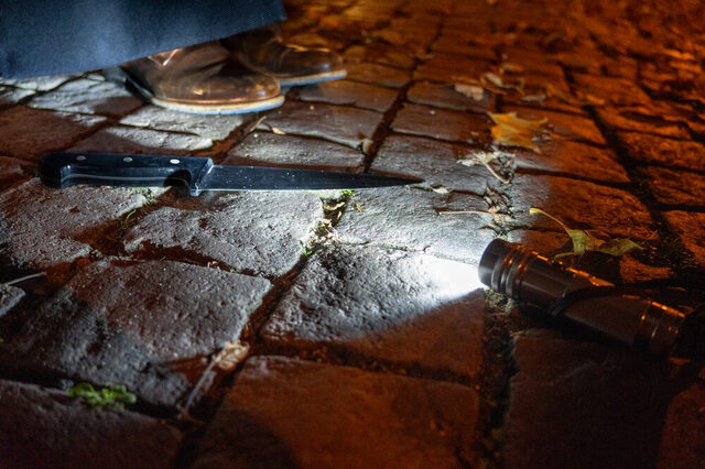 Ein Messer liegt auf einem gepflasterten Platz angestrahlt von einer Taschenlampe.