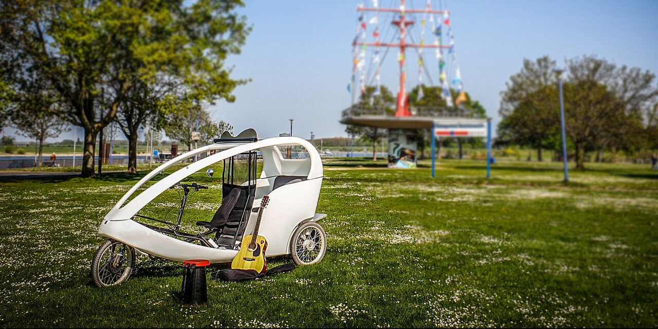 Rikscha "Rieke" steht auf der Mühlenweide, im Hntergrund der Fahnenmast