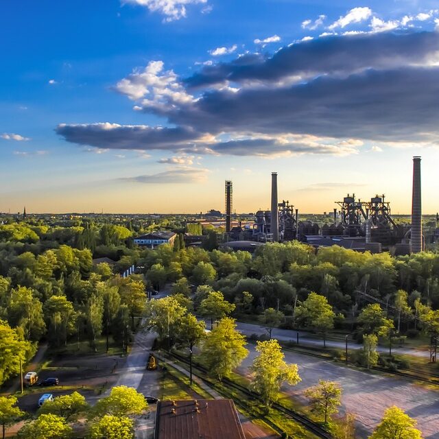 Landschaftspark Duisburg mit Bäumen im Vordergrund und Industrie im Hintergrund
