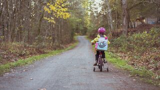 Mädchen auf einem Fahrrad auf einem Waldweg