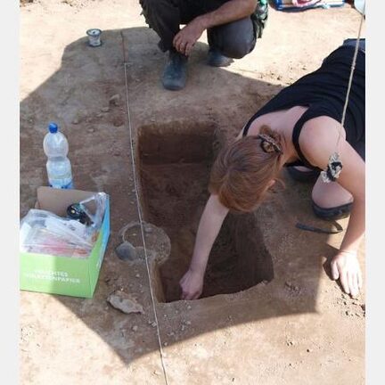 Die Archäologin legt eine Urne frei