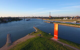 Orangefarbene Stele am Flussufer - Rheinorange genannt.